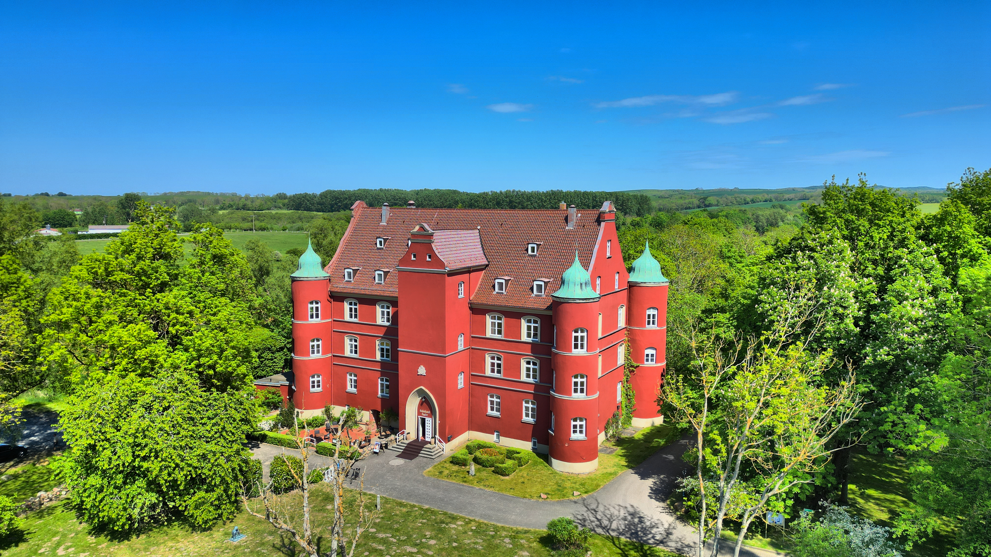 Ein rotes Schloss ist umringt von Bäumen.